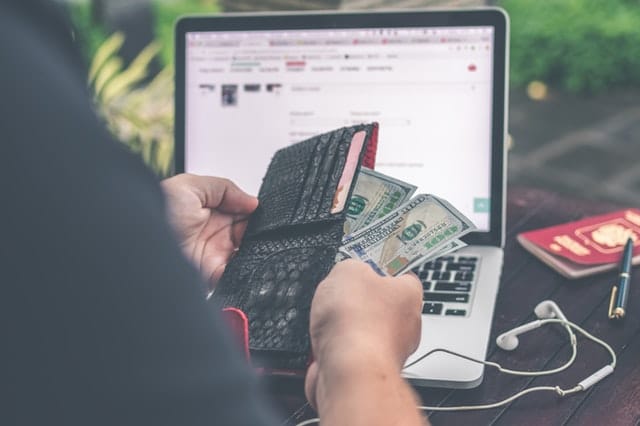 Man opening his wallet while looking at a checkout screen online 