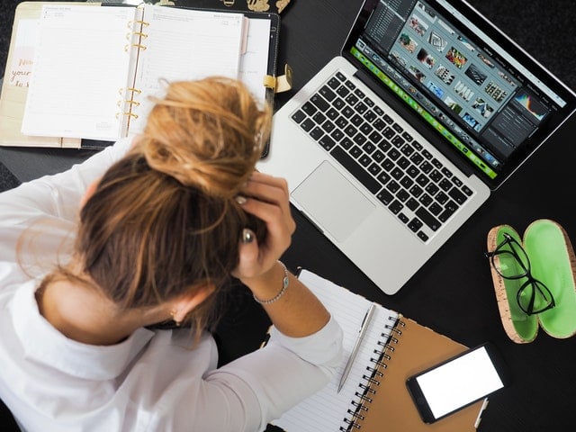 employee sitting at a computer with head in her hands