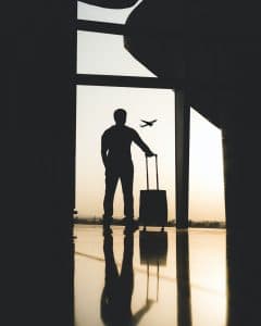 Man stands near airport window with briefcase